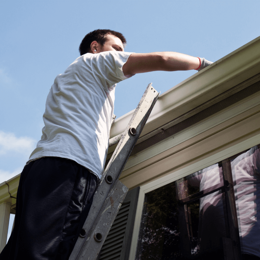 Man on ladder checking gutter