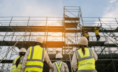 Safety officers in high visibility safety uniform looking up at workers on scaffolding